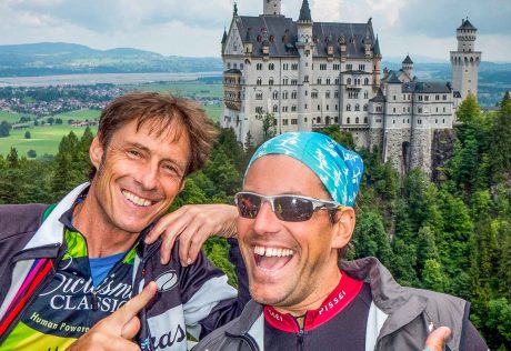 Two bikers on the Munich to Verona tour posing near a castle