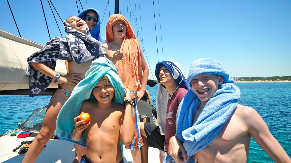 Kids on a sailboat relaxing in the Sardinian sun