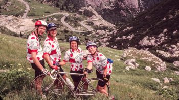 Bikers posing in front of a winding road in the Dolomites
